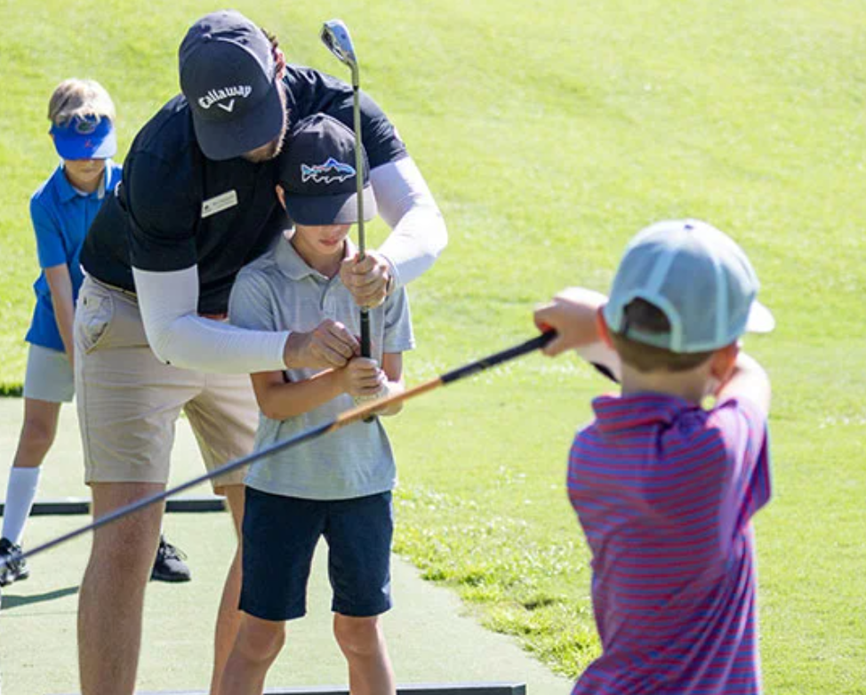 Older student showing a younger child how to putt